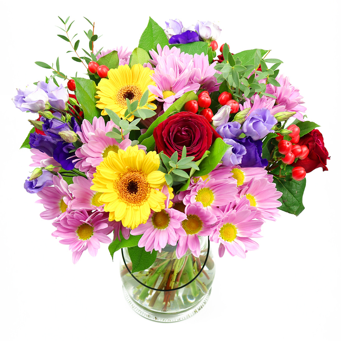 In this photograph, a lush mixed bouquet stands proudly in a clear glass vase against a pure white background, its colours and textures reminiscent of a vibrant flower stall tucked just off Abbots Langley's main streets. At the centre, sumptuous deep red roses unfold in velvety spirals, giving the arrangement a timeless, romantic core. Flanking them are golden-yellow gerbera daisies with warm brown-orange centres, their wide, flat faces bringing a burst of sunshine energy that feels instantly uplifting. Surrounding this central cluster, soft pink and pale lilac chrysanthemums and daisies create a halo of gentle colour, each bloom composed of fine, feathery petals that invite the eye to linger on their detail. Slender stems of lisianthus, in rich purple and soft lavender shades, weave through the bouquet like elegant ribbons, their bell-shaped blossoms adding a cool sophistication. Scattered pockets of bright red hypericum berries sit nestled among the petals, like tiny polished marbles, lending structure and playful contrast. Layers of greenery in varying tones-from dark, glossy leaves to lighter, more delicate sprigs-frame the flowers and push the colour forward, giving the design a natural, garden-fresh fullness that would look at home in a living room overlooking Leavesden or Kings Langley. The clear vase reveals the neatly cut stems and the clarity of the water, underscoring the care taken in conditioning each flower. The arrangement radiates a sense of cheerful celebration and heartfelt thoughtfulness, ideal as a thank-you gift, a birthday surprise, or a centrepiece for a cosy family gathering in Abbots Langley.